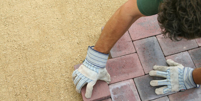 image showing a person wearing gloves laying down block paving