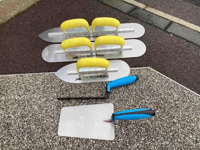 overhead photo of resin bound trowels with yellow and blue handles for resin bound installation